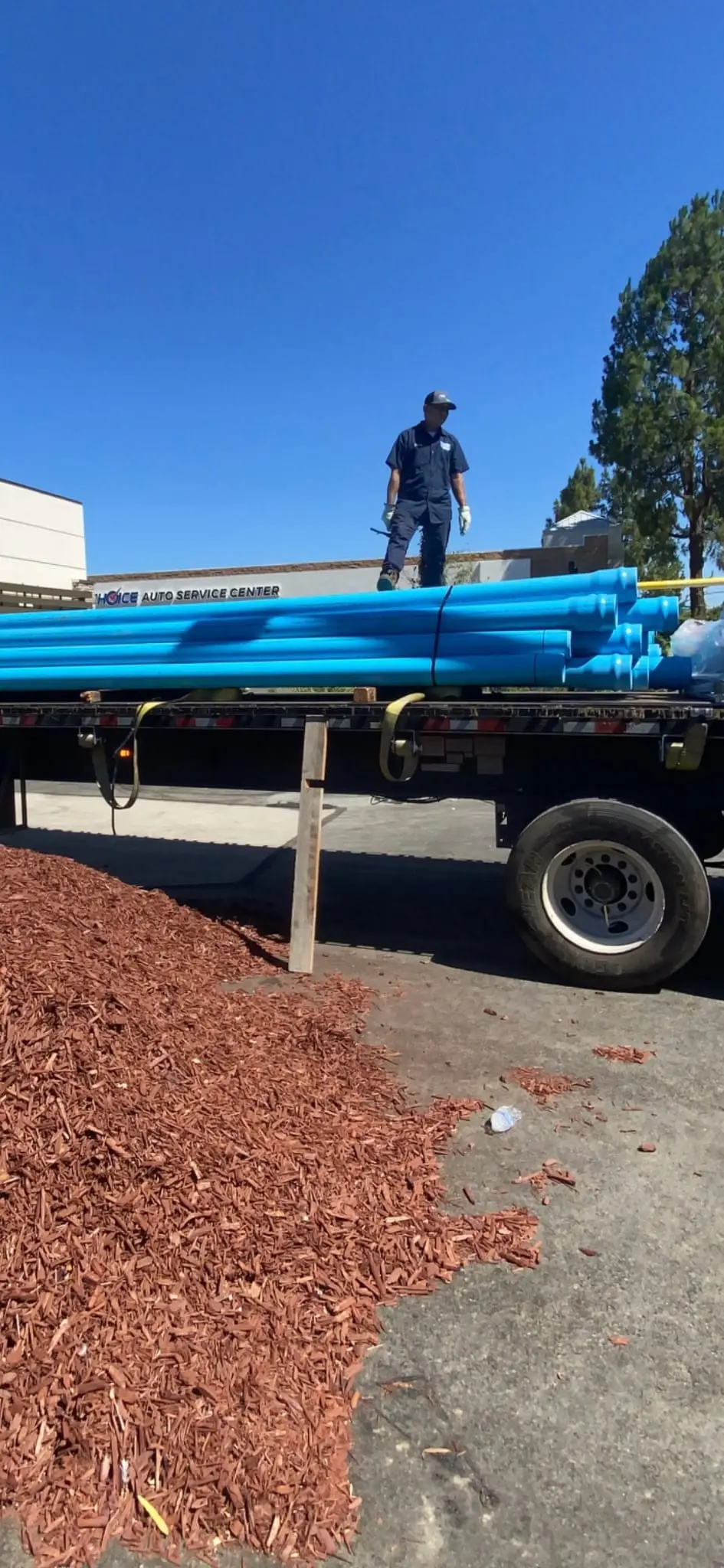 Flatbed truck loaded with blue underground fire main pipe on a Bay Area job site.